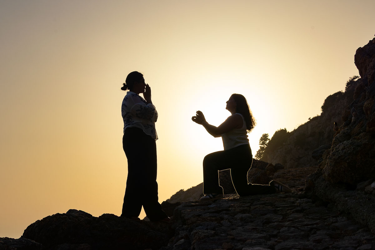 Silhouette photography of two women during a romantic tuscan beach engagement , framed against the glowing horizon with dramatic natural backlighting.