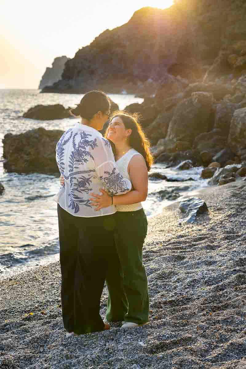 Relaxed beach photoshoot of an engaged couple smiling together along the shoreline of Monte Argentario during the golden evening light.