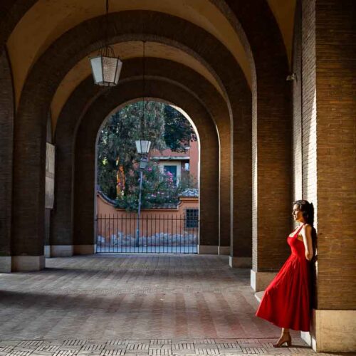 Editorial-style portrait captured beneath the elegant portico of Santa Sabina, using architectural lines, soft morning shadows, and geometric shapes to create a refined travel image.