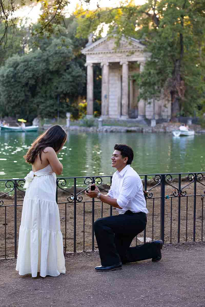 Kneeling down to ask her girlfriend in marriage in one of Rome most scenic lakeside location in Villa Borghese