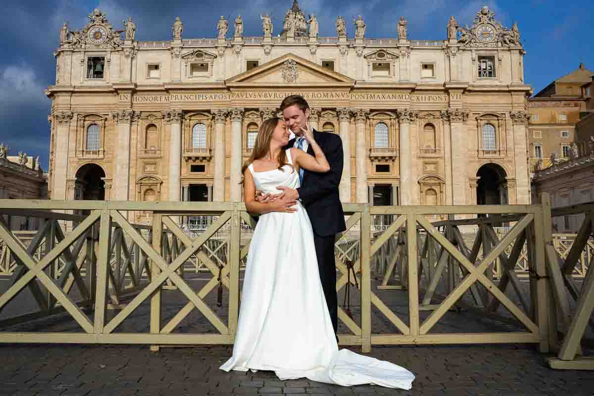 Bride and groom posed against the monumental façade of St. Peter’s Basilica, with the photographer using the grand architecture for a formal portrait