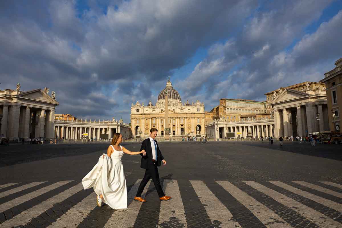 Pair crossing Via della Conciliazione hand in hand, with St. Peter’s Basilica in the distance forming the backdrop for this Rome street photograph
