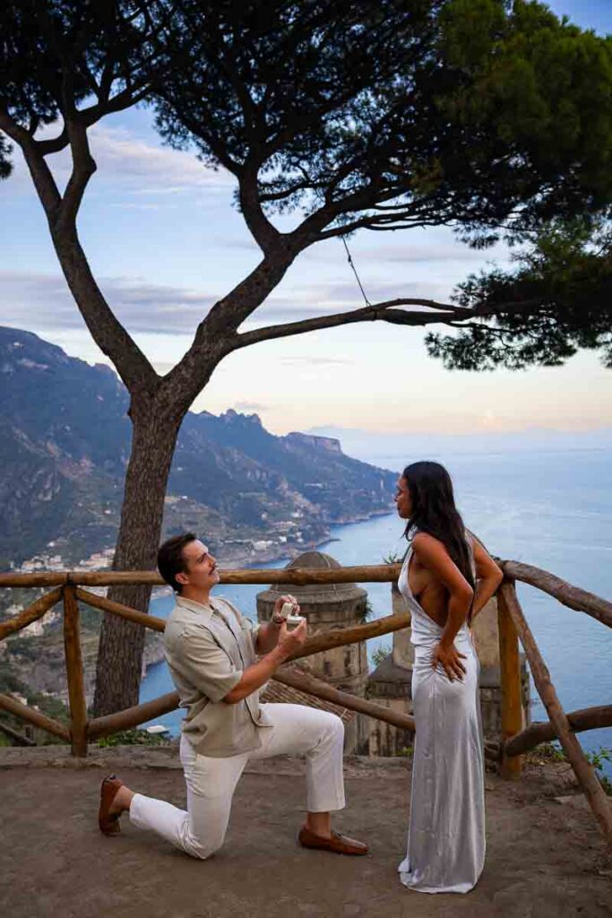 A surprise marriage proposal at Villa Rufolo during the blue hour, with the man kneeling against the iconic twin-domed Church of the Annunziata background