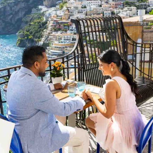 A couple enjoying an outdoor meal on a balcony overlooking the vertical hill scenery.