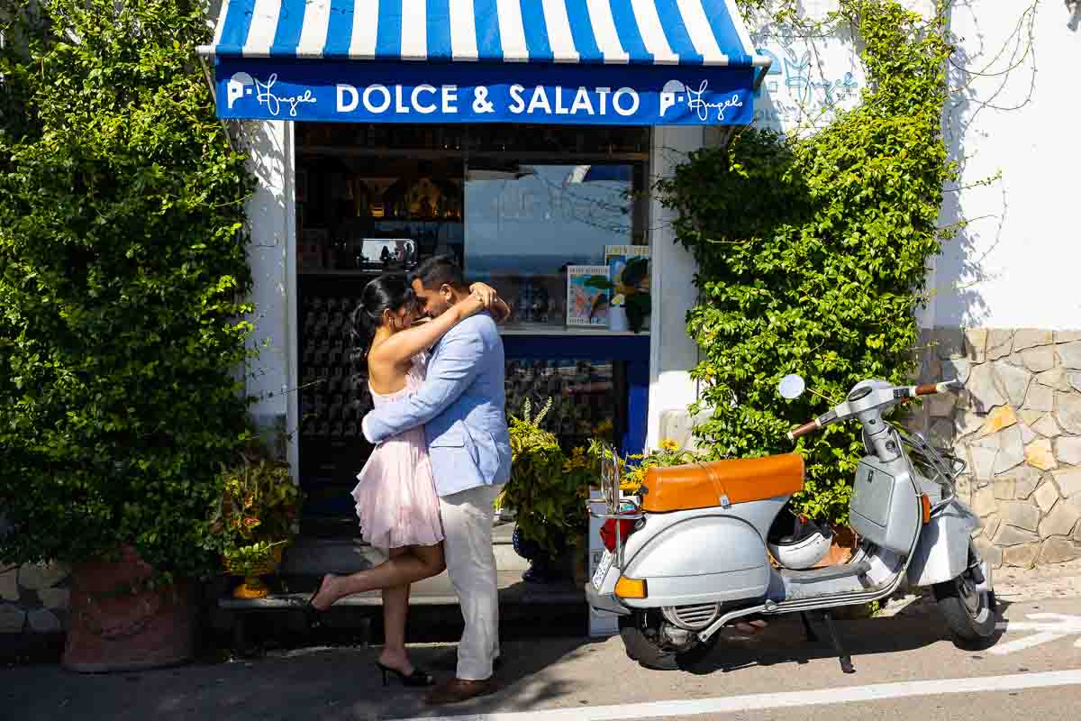 Lifestyle couple photography capturing a loving moment together in front of a charming local storefront.