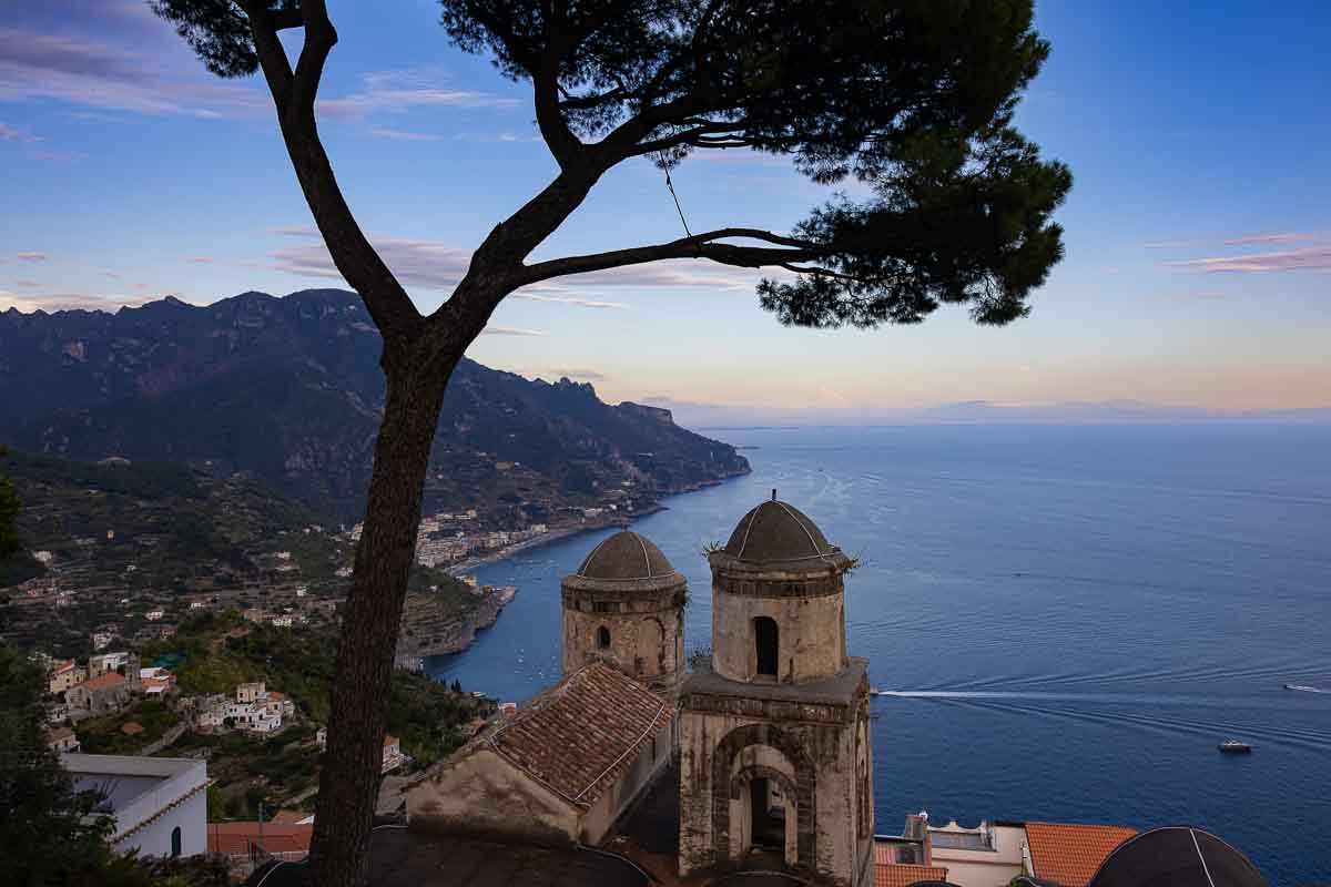 A breathtaking post-sunset landscape photograph of the Amalfi Coast line glowing under the deep twilight blue hour skies.