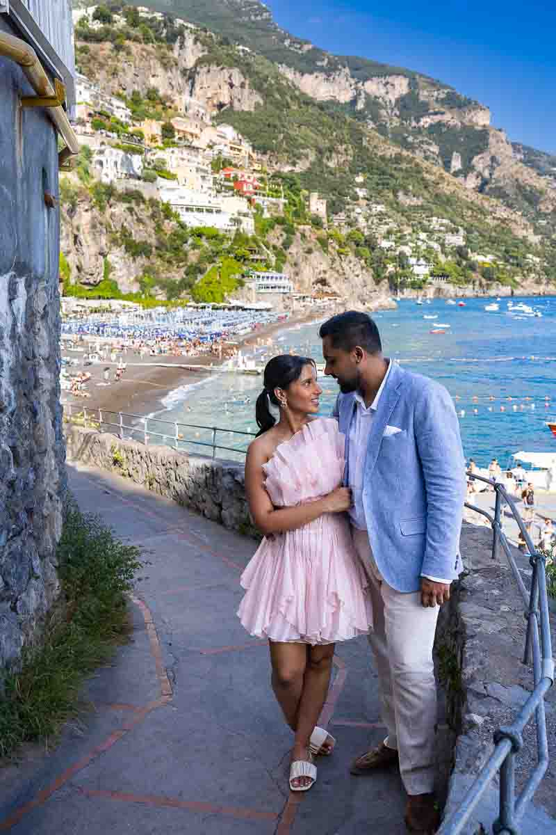 Postcard-style capture of a traveling pair exploring the narrow walkway toward Fornillo beach.