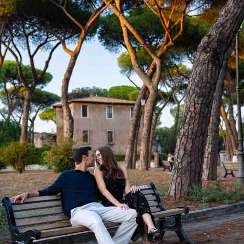 Romantic photo session of a couple sitting down on a wooden bench in park in Rome Italy